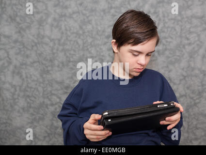 Teenage Boy with Special Needs Playing with a Tablet Stock Photo