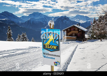 Welcome sign urging skiers to skiing slowly in Alpine ski station in the Swiss Alps in winter Stock Photo