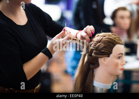Pretty female hairdresser/haidressing apprentice/student training on an apprentice head Stock Photo