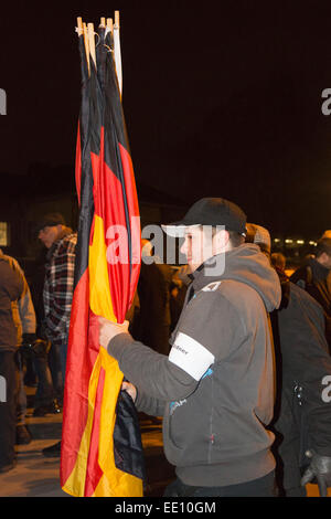 05/01/2015. Cologne, Germany. A right-wing protester clutches German national flags before handing them out to supporters. About two hundred right-wing protesters followed a call to demonstate against the Islamisation of Europe in Cologne, Germany. The KÖGIDA demonstrators were far outnumbered by thousands of left-wing protesters. This follows the PEGIDA demonstrations in Dresden that keep attracting a large number of followers. PEGIDA stands for 'Patriotic European Against the Islamisation of Europe'. As a protest, Cologne Cathedral - usually illuminated at night - remained dark in protest ag Stock Photo