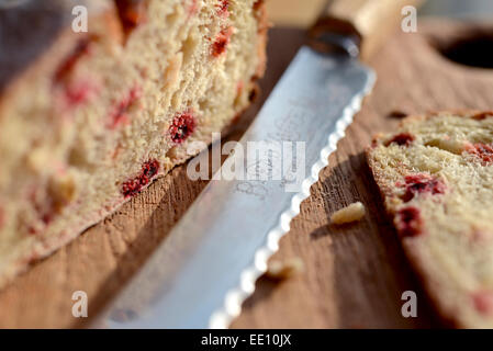 Bread knife inscribed with ornate font spelling bread knife and a loaf of homemade, rustic beetroot bread on  a textured wooden chopping board. Stock Photo