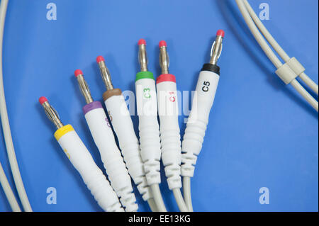 Closeup detail of six electrode jack plugs from an ECG machine in a medical center hospital on blue table background Stock Photo
