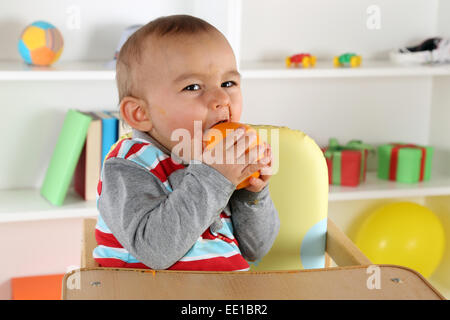 Little baby child eating healthy orange fruit Stock Photo