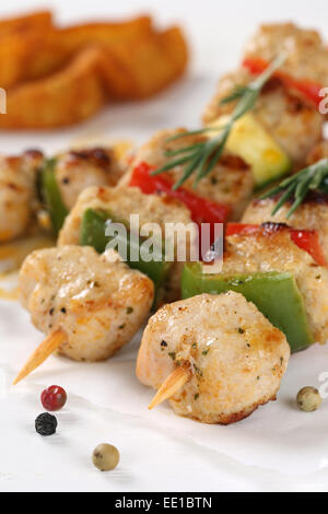 Grilled chicken or turkey meat skewers with potato wedges and vegetables on a wooden board Stock Photo
