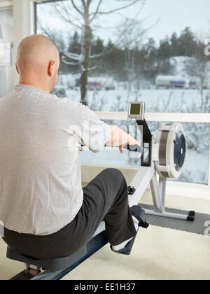 Mature man takes care of his health and he rowing in the gym Stock Photo