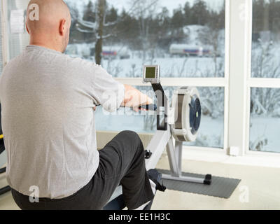 Mature man takes care of his health and he rowing in the gym Stock Photo