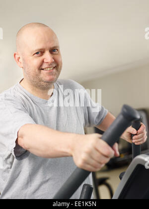 Close up, mature man takes care of his health and he use elliptical trainer in the gym Stock Photo