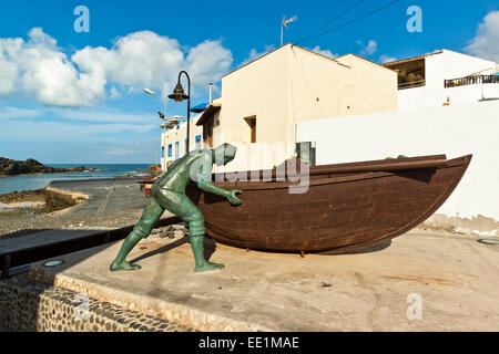 Boat with statues of fishermen at the old harbour in this north west coast village, El Cotillo, Fuerteventura, Canary Islands Stock Photo