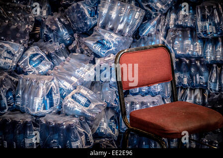 A red chair and and heap of water bottles in a storage area of the cafe on Robben Island, Cape Town, South Africa. Stock Photo