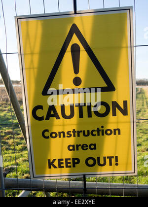 A 'Caution construction area. Keep out!' sign on a fence at a house building site in Watchfield, Oxfordshire,UK