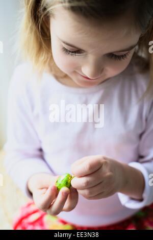 Liitle girl unpacking Easter egg, close-up Stock Photo