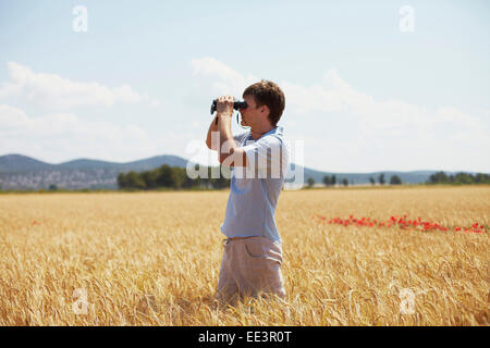 Man On Field Looking Through Binoculars, Croatia, Dalmatia, Europe Stock Photo