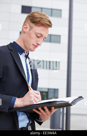 Young consultant checking contract in folder in front of the office Stock Photo