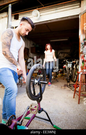 Young man in workshop repairs BMX bicycle Stock Photo
