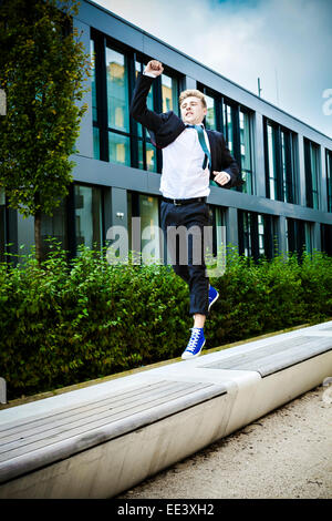 Young businessman jumps in air cheering, Munich, Bavaria, Germany Stock Photo