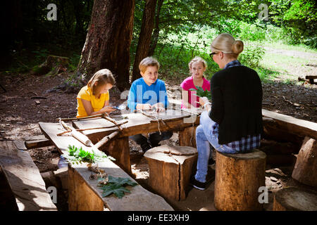 Children and teacher crafting in forest camp, Munich, Bavaria, Germany Stock Photo