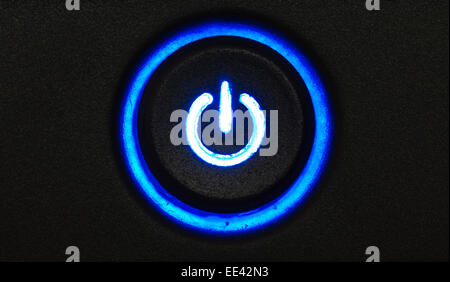 Blue glowing power button on a black pattern background Stock Photo