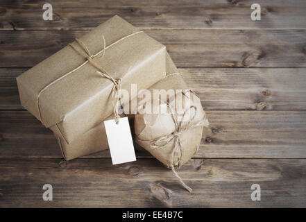 Heart and box wrapped in brown kraft paper with a price tag,  on wooden table closeup Stock Photo