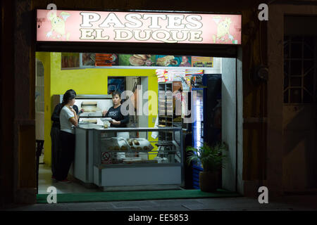 A Mexican woman in a small bread  and pastry shop, at night,  in the historic center of Puebla, Mexico Stock Photo