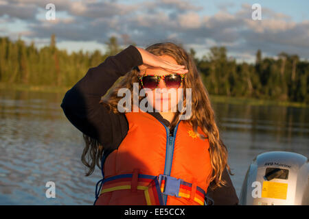 Girl shielding eyes from the sunlight, Lake of The Woods, Ontario, Canada Stock Photo