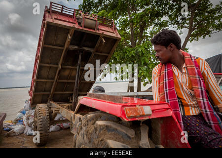 A worker operating heavy equipment vehicle during a river erosion control project on the bank of Rupnarayan river in Tamluk, West Bengal, India. Stock Photo