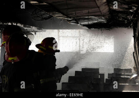 Dhaka, Bangladesh. 14th Jan, 2015. Firefighters try to extinguish fire of a burning bus during the nonstop blockade called by Bangladesh Nationalist Party (BNP) in Dhaka, Bangladesh, Jan. 14, 2015. With the death of four more people Wednesday, the number of deaths reached 17 on the ninth day of the opposition-led indefinite blockade in Bangladesh. Credit:  Shariful Islam/Xinhua/Alamy Live News Stock Photo