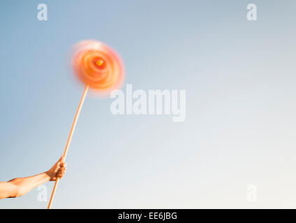 Hand holding pinwheel toy spinning in the wind. Conceptual image of freedom, carefree lifestyle and having fun. Stock Photo