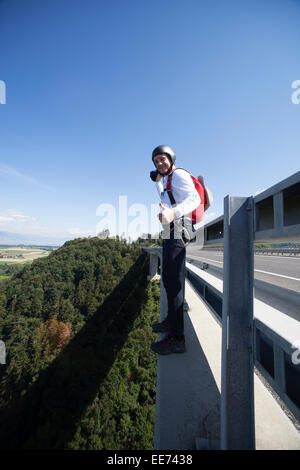This man is going to jump from the bridge. It looks like he is very excited to do this BASE jump and thereby he smiles a lot. Stock Photo