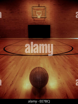 Basketball on floor of empty basketball court Stock Photo