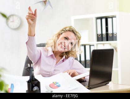 businesswoman throwing paper airplane in office Stock Photo