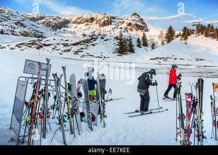 Skiers wearing ski helmets preparing to descend ski slope in winter sports resort in the Alps Stock Photo