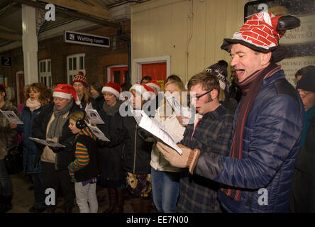 People carol singing on Farnham train station to fundraise for Marie Curie cancer charity, Farnham, Surrey, UK. Stock Photo