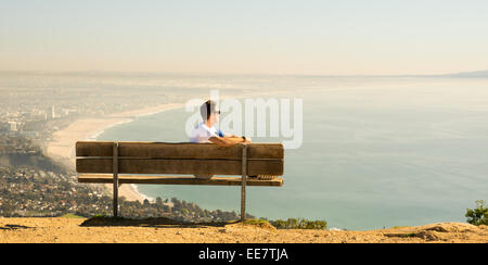 Guy sitting on a bench. He is clearly enjoying the beautiful view. He is relaxing. He thinks, This is Paradise. Stock Photo