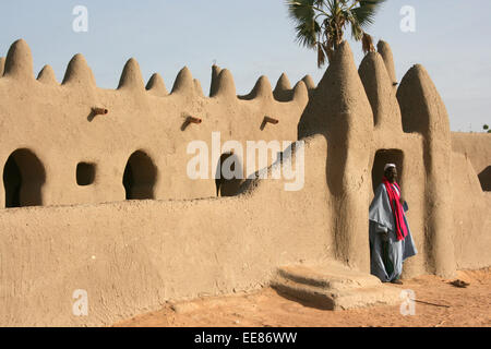 An imam stands at the entrance to a traditional mud-brick mosque in a village near Djenne, Mali Stock Photo