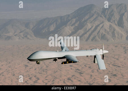 Armed MQ-1 Predator unmanned aircraft carrying 2 Hellfire missiles flying over desert landscape Stock Photo