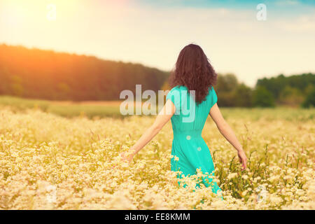 Young happy girl walking on the flower meadow Stock Photo