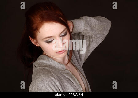 Beautify young teen girl wearing a grey hoodie on black background. 13th April 2013 Stock Photo