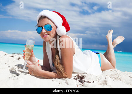 Happy woman with glass of champagne celebrating Christmas on beach Stock Photo