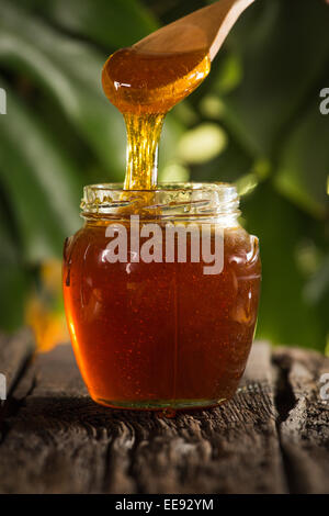 Close-up shot of flowing honey over green background Stock Photo