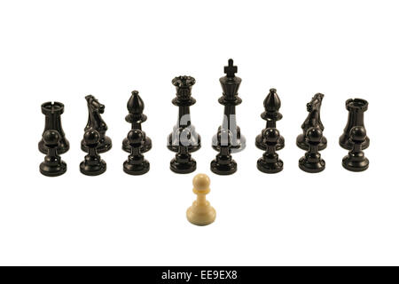 White pawn standing in front of the aligned black chess pieces. Stock Photo