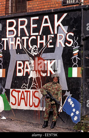 BELFAST NORTHERN IRELAND - October 1982; British Army Soldier standing in front of Republican Mural depicting Margaret Thatcher's stand against the Republican Hunger Strikers in the Maze Prison. Stock Photo