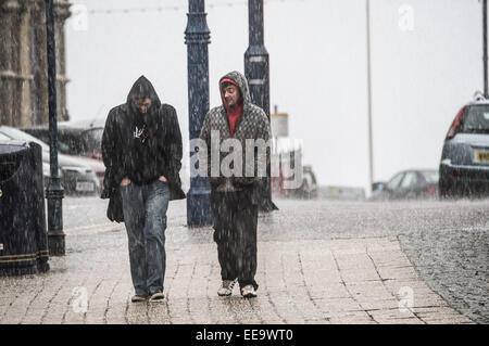 Aberystwyth, Wales, UK. 15th January, 2015. UK weather. Overnight stormy weather brought driving rain and heavy hailstorms to Aberystwyth Wales. Two men get caught in a hailstorm in the morning Yellow wind and flood warnings are in place for most of the UK today with severe gale force winds gusting up to 70mph in places making for 'tricky travel conditions”. Snow is forecast for higher ground in North Wales and Scotland Credit:  keith morris/Alamy Live News Stock Photo