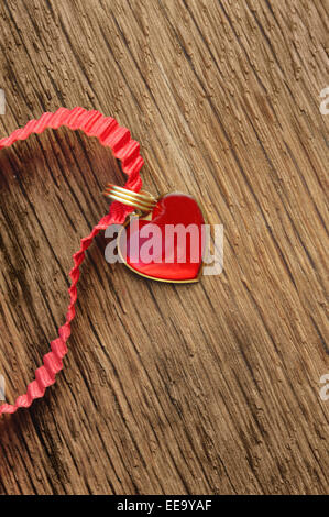 little red heart shaped pendant on wooden background Stock Photo