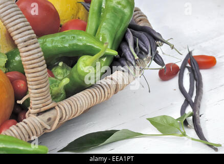 Fresh seasonal vegetables in wicker basket on white wooden table Stock Photo