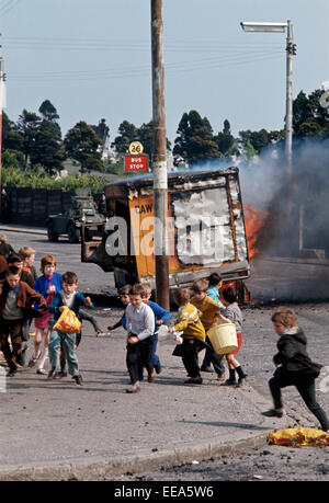 BELFAST, NORTHERN IRELAND - JUNE 1972. Children running away from burning Hijacked Vehicle in West Belfast during The Troubles. Stock Photo