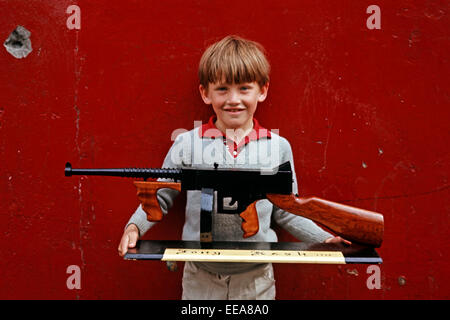 INTERNMENT ART, LONG KESH, NORTHERN IRELAND - JUNE 1972. Child holding Wooden Replica of a Thompson Machine Gun made by Long Kesh Prisoners during The Troubles. Stock Photo