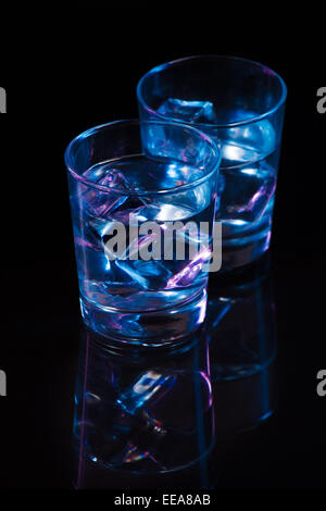 Two glasses of vodka with ice cubes against  the background of deep blue glow. Stock Photo