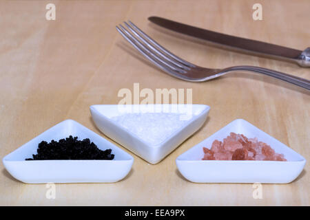 Three types of salt with silverware in background Stock Photo