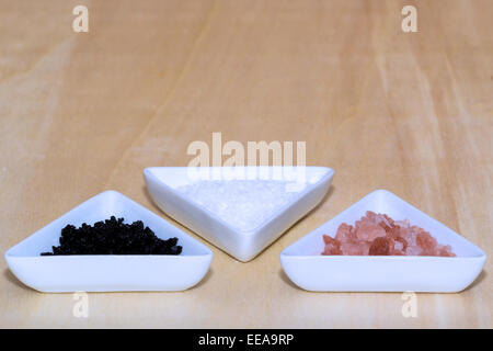 Three types of salt in white triangular shaped ceramic bowls Stock Photo