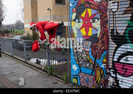 Man dressed as Santa Claus jumps over a fence near to Brick Lane, London, UK. As Christmas comes to a close he is seen running away as if guilty of some kind of offense. Stock Photo